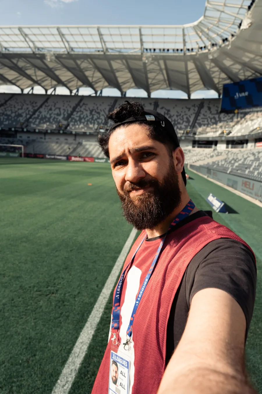 Chris Andrawes on the field at a stadium, wearing a media bib and lanyard