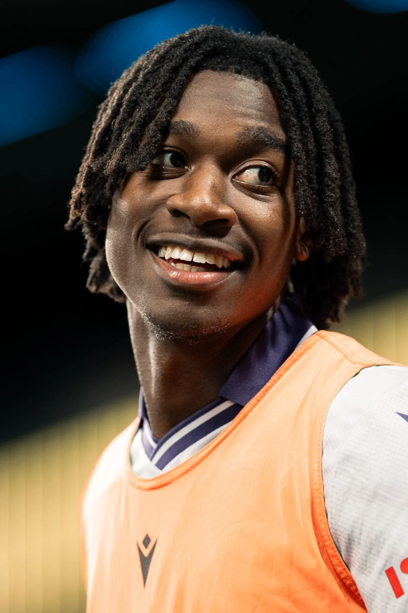Smiling player in an orange training bib on the sidelines