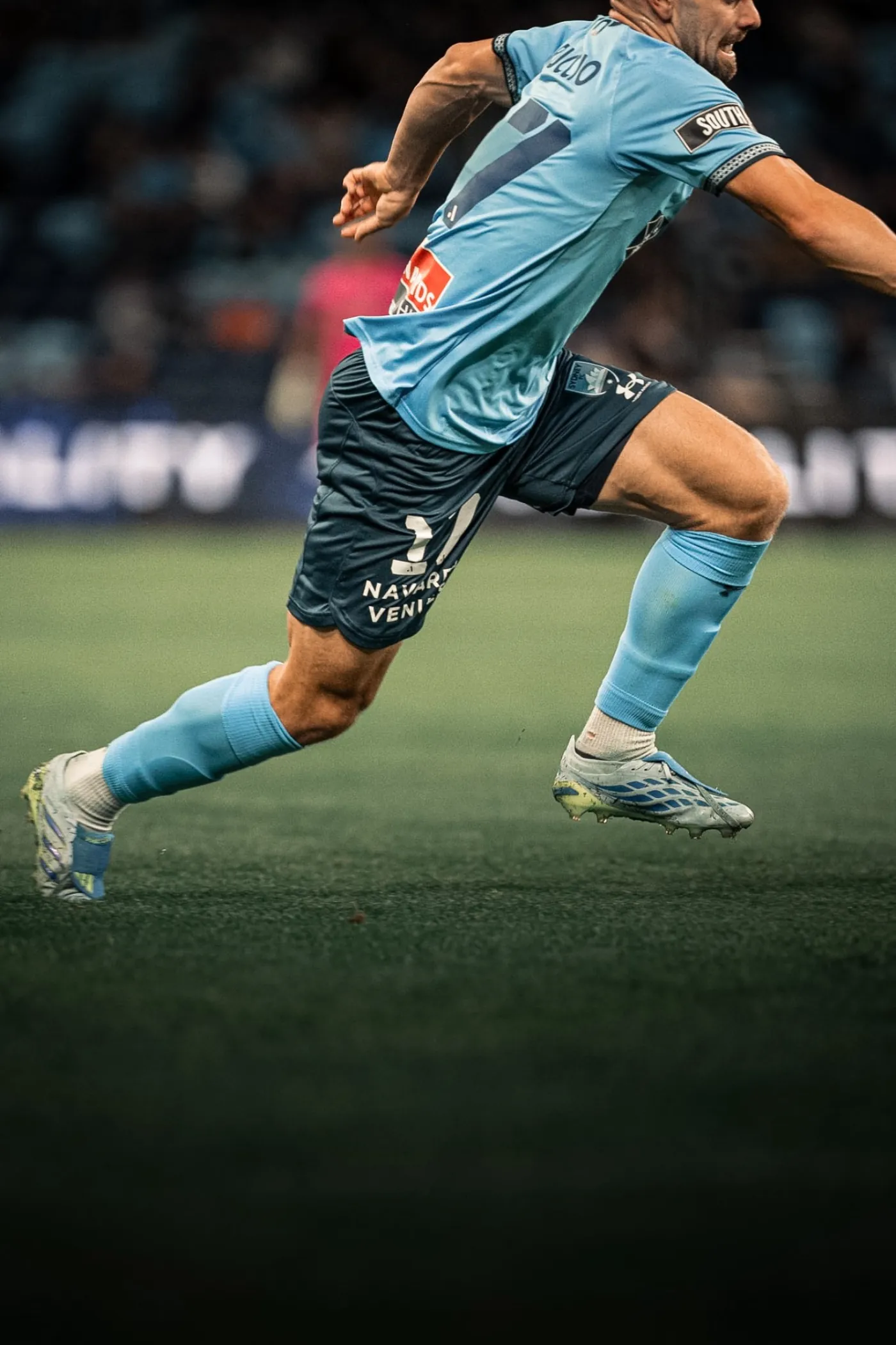 Sydney FC player sprinting on the pitch, mid-stride